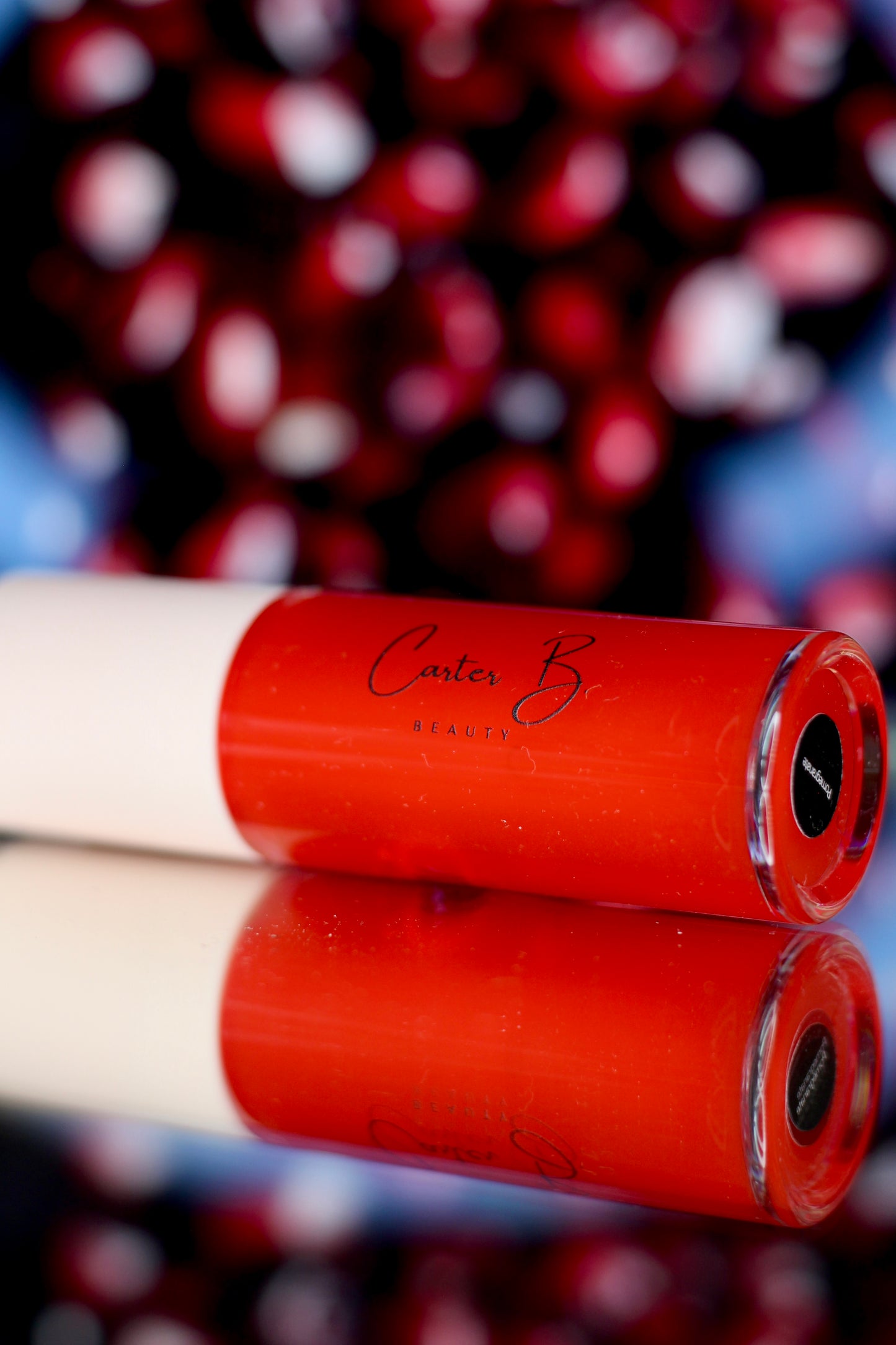 Carter B. Beauty Lippenöl in der Farbe POMEGRANATE – feuchtigkeitsspendendes, natürliches Lip Oil mit roten Akzenten und pflegender Formel, präsentiert vor einem roten Hintergrund. (liegend)