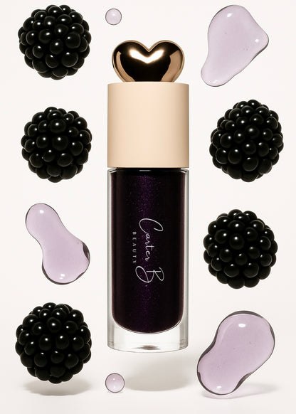 Carter B. Beauty Lippenöl in der Farbe BLACK CURRANT – feuchtigkeitsspendendes, natürliches Lip Oil mit beerigen Akzenten und pflegender Formel, präsentiert vor einem dunklen Hintergrund. (stehend mit Brombeeren)