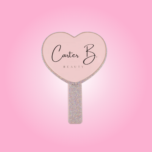 Ein herzförmiger Handspiegel, mit Glitzersteinchen besetzt (rosafarbener Hintergrund) - von Carter B. Beauty