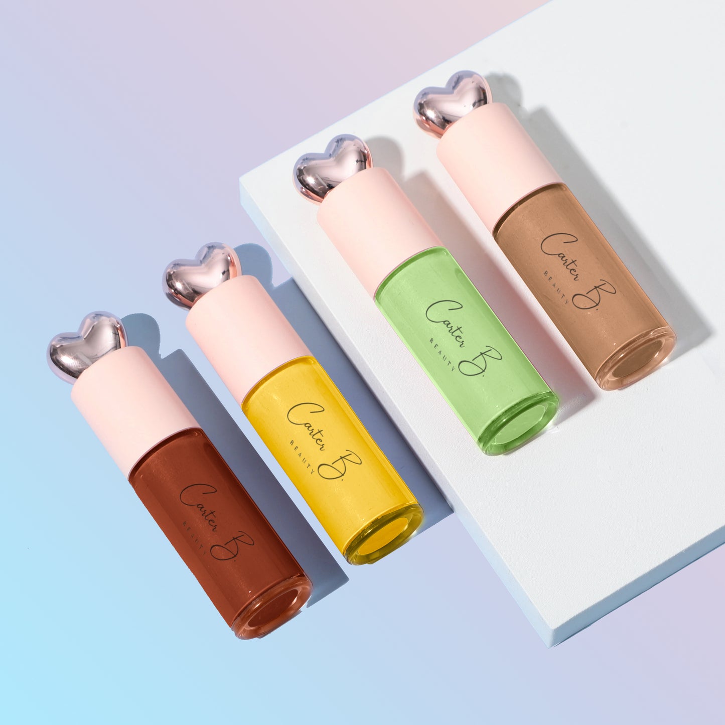 Vier neue Lippenöle von Carter B. Beauty. In einem ROSEWOOD, GINGER, AVOCADO und LATTE vor einem blau-rosanden Hintergrund (nebeneinander gereiht)