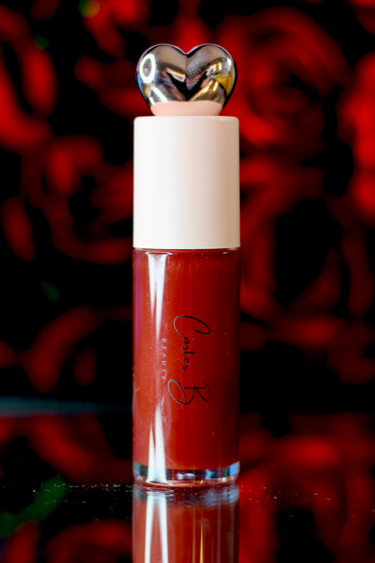 Carter B. Beauty Lippenöl in der Farbe ROSEWOOD – feuchtigkeitsspendendes, natürliches Lip Oil mit rosenholzfarbenden Akzenten und pflegender Formel, präsentiert vor einem strahlenden rosigem Hintergrund. (stehend)
