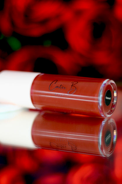 Carter B. Beauty Lippenöl in der Farbe ROSEWOOD – feuchtigkeitsspendendes, natürliches Lip Oil mit rosenholzfarbenden Akzenten und pflegender Formel, präsentiert vor einem strahlenden rosigem Hintergrund. (liegend)