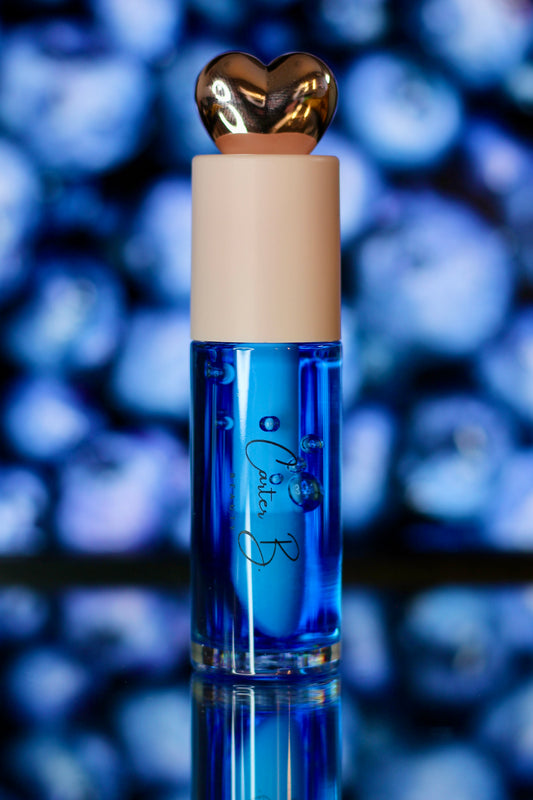 Carter B. Beauty Lippenöl in der Farbe BLUEBERRY – feuchtigkeitsspendendes, natürliches Lip Oil mit kühlen Akzenten und pflegender Formel, präsentiert vor einem beerigen Hintergrund. (stehend)