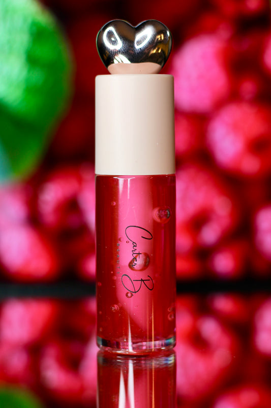 Carter B. Beauty Lippenöl in der Farbe RAPSBERRY – feuchtigkeitsspendendes, natürliches Lip Oil mit pinken Akzenten und pflegender Formel, präsentiert vor einem beerigen Hintergrund. (stehend)